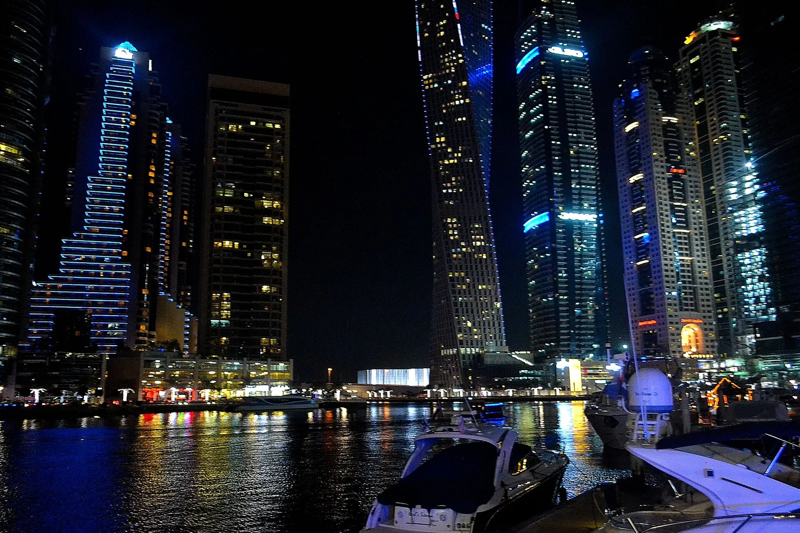 Dubai Marina towers and yachts lit up along the water at night
