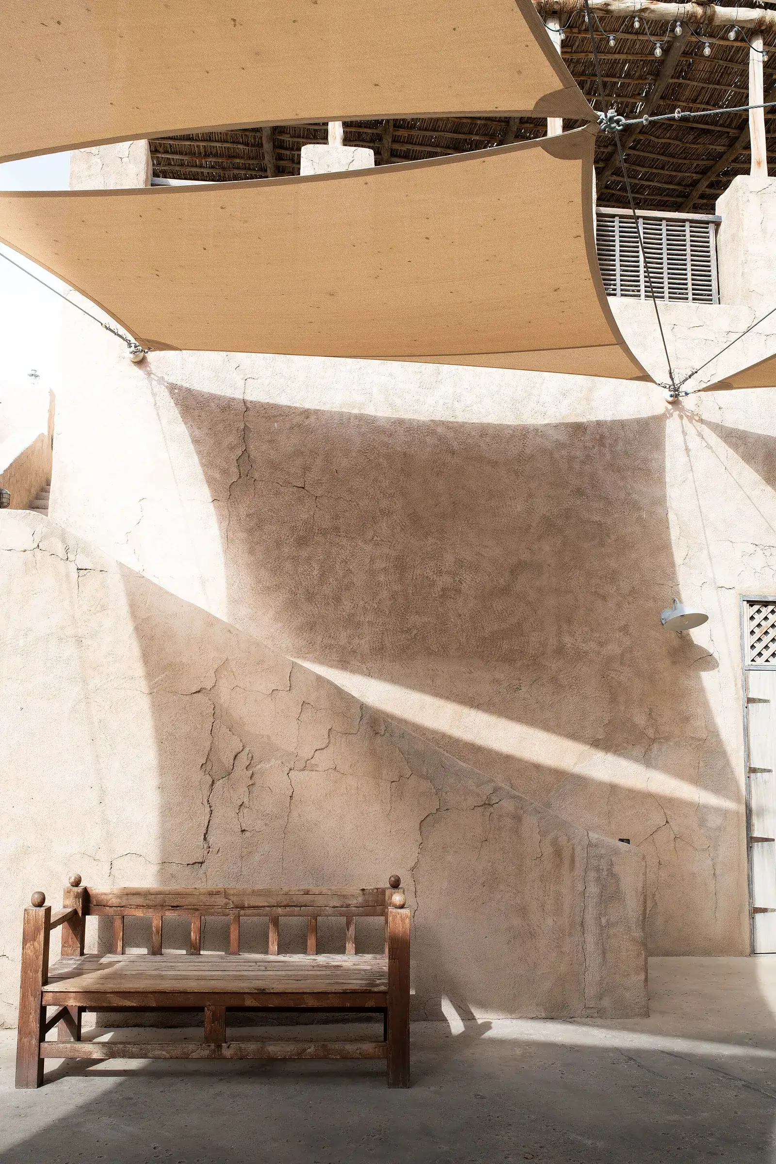Shaded courtyard with a wooden bench and coral-stone walls in the Al Fahidi Historical Neighbourhood