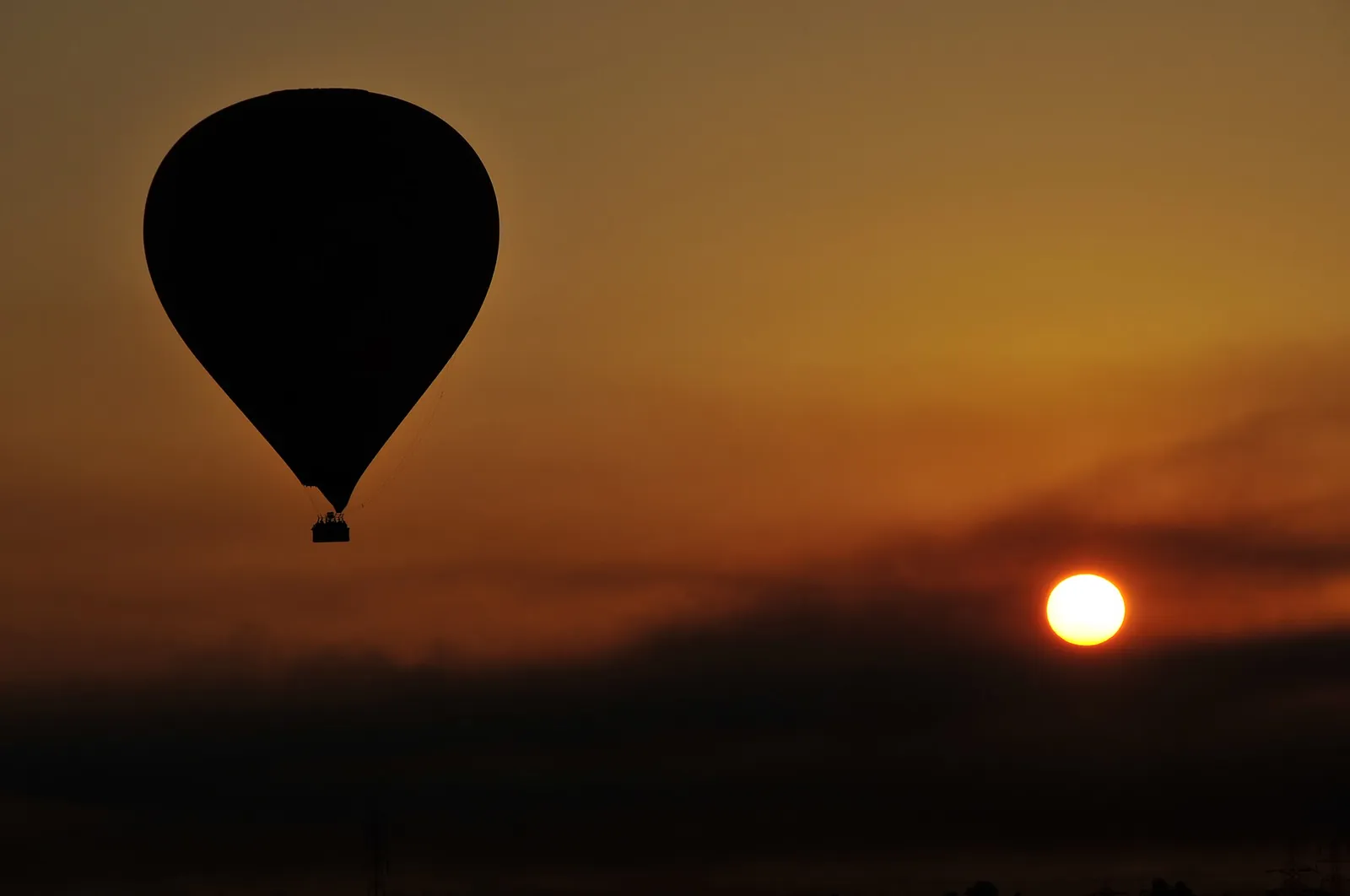 Hot air balloon silhouetted against the dawn sky over Luxor