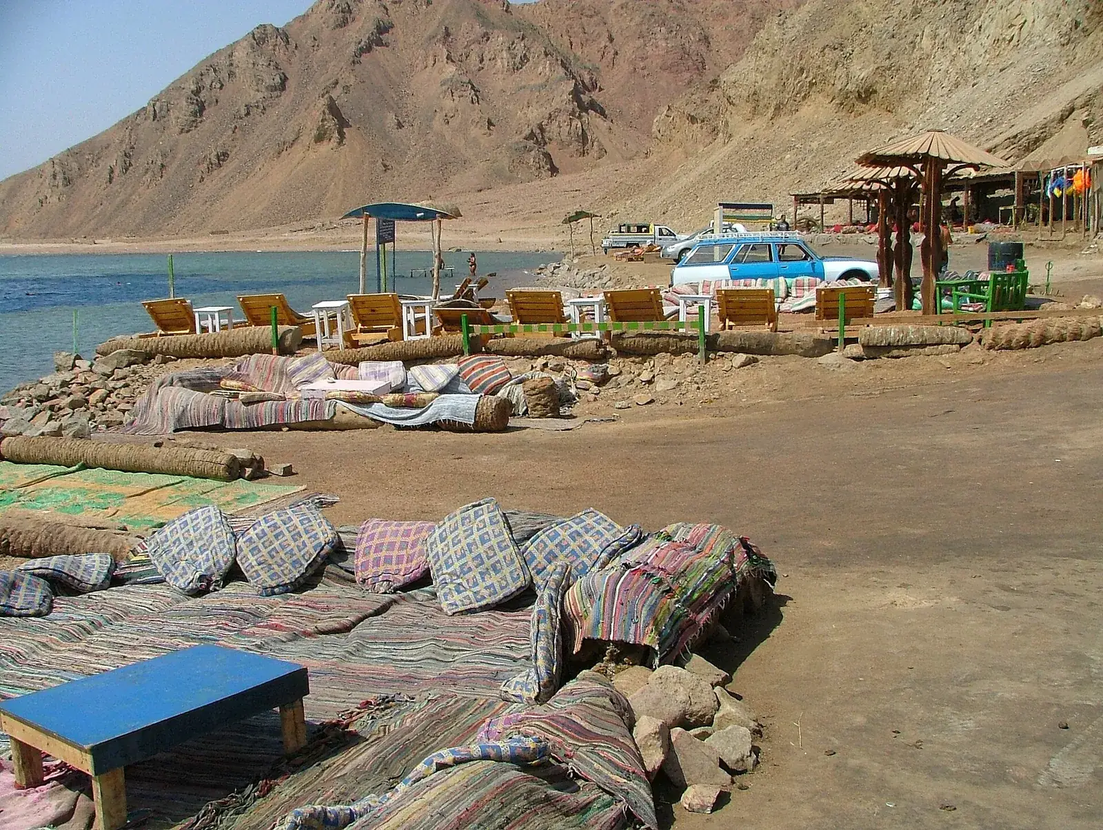 Rug-covered Bedouin seating and beach cafés on the shore at the Blue Hole north of Dahab