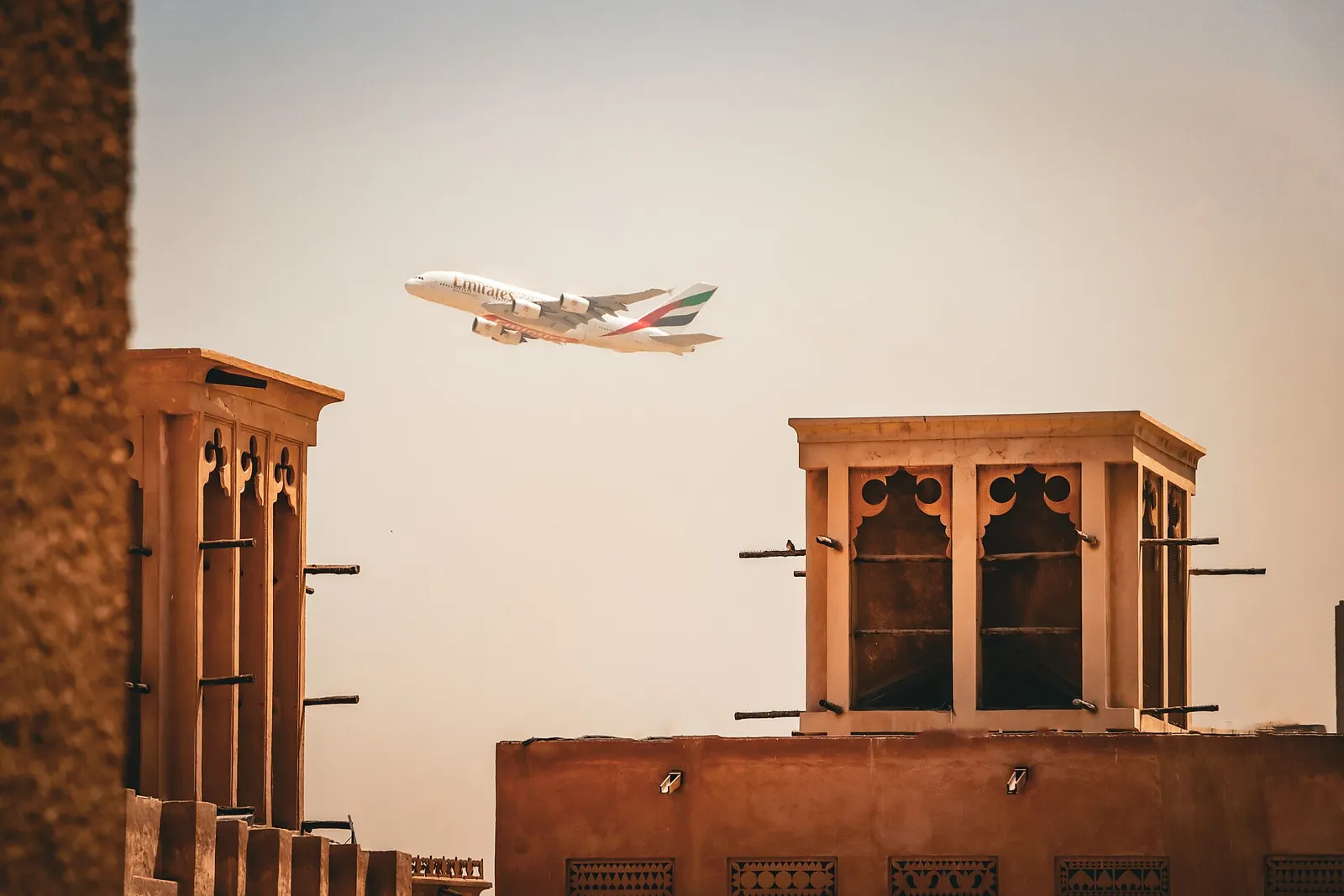 Wind towers in the Al Fahidi Historical Neighbourhood in Old Dubai with a plane passing overhead