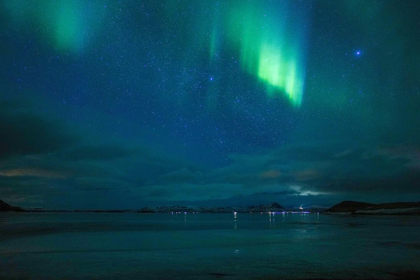 Green northern lights over the sea on a clear winter night in northern Norway