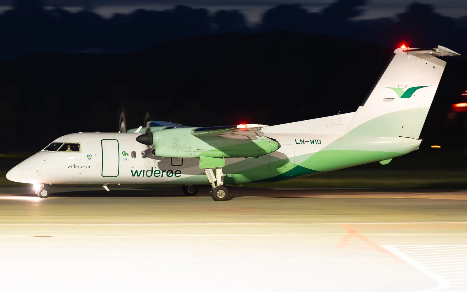 Widerøe Dash 8 turboprop taxiing at night at a Norwegian regional airport