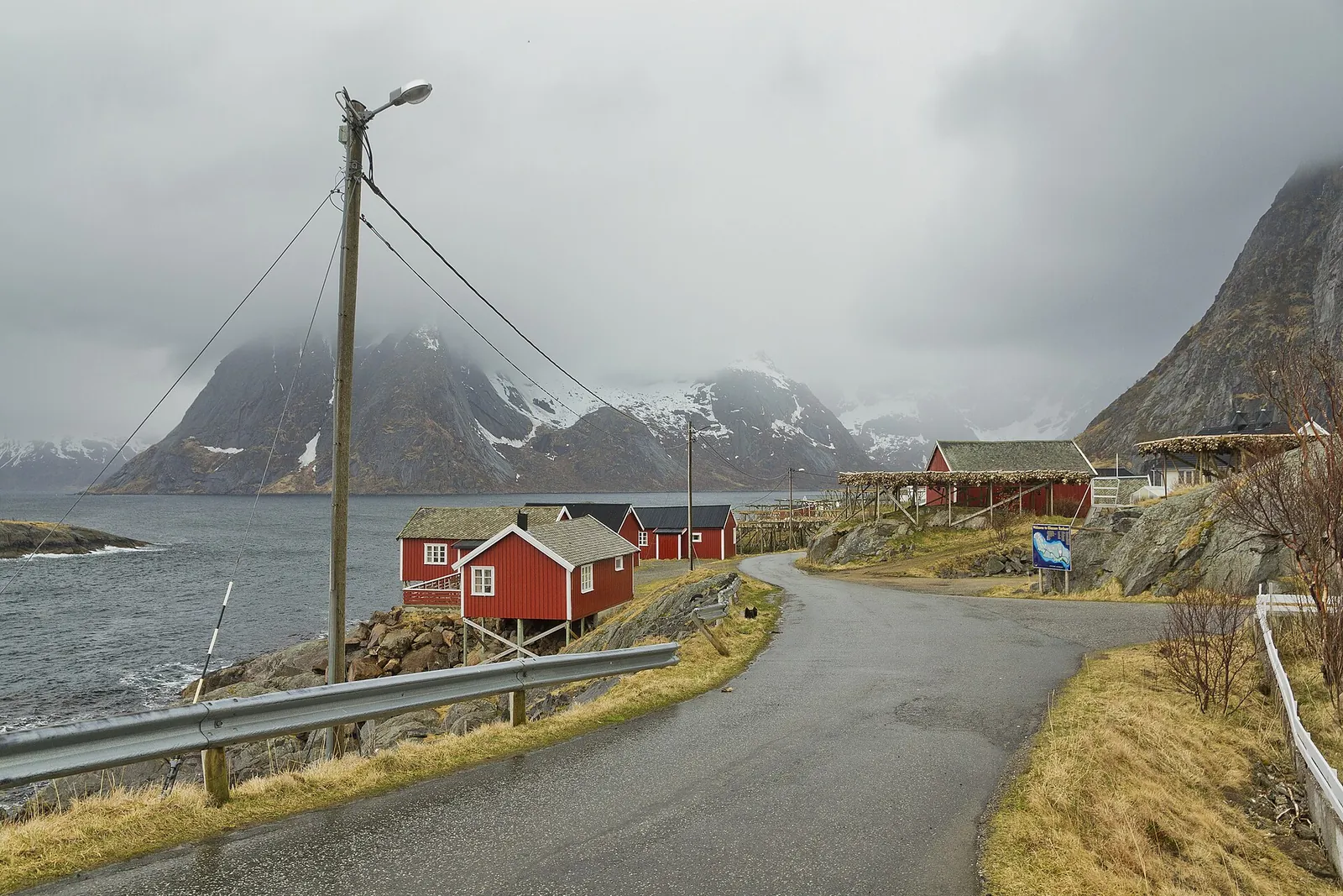 Red fishermen's cabins on the shore at Hamnøy with steep mountains behind, Lofoten, Norway