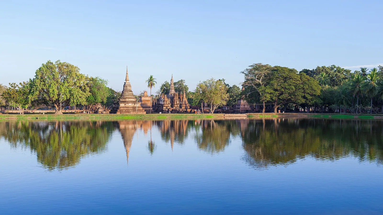 Brick chedis of Wat Mahathat reflected in a pond in Sukhothai Historical Park